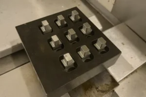 Metal blocks secured in a fixture on a CNC machine, ready for precise machining in a production setup.