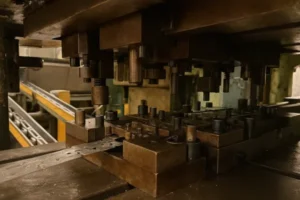 Close-up of a metal stamping press machine in action, showing multiple punches and dies shaping metal parts.