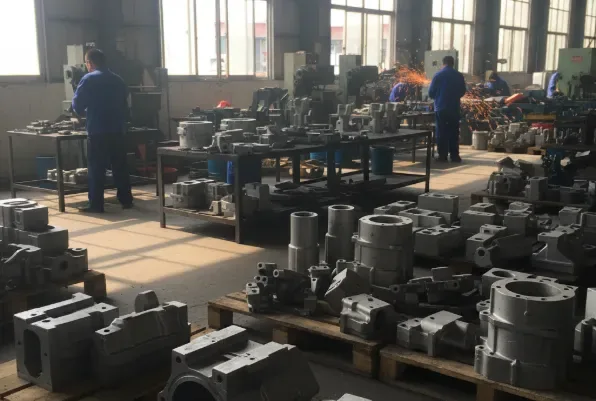 Machining workshop with workers and many finished metal housings and blocks on pallets, showing large-scale production capacity.