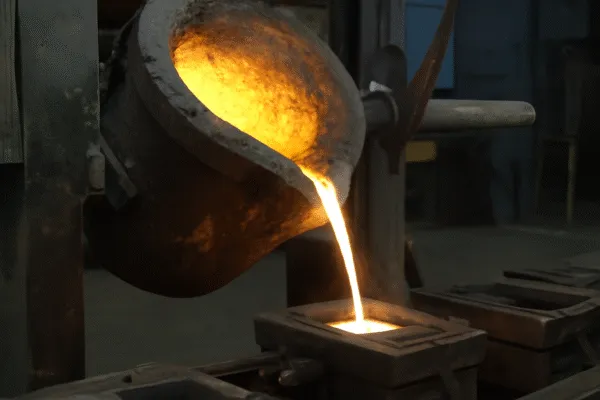 Molten metal being poured into a mold from a crucible during a metal casting process.