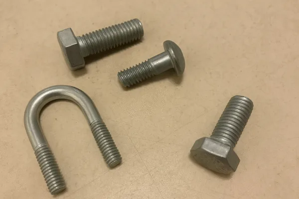 U-bolt and assorted metal fasteners on a workbench, including hex bolts and a carriage bolt.