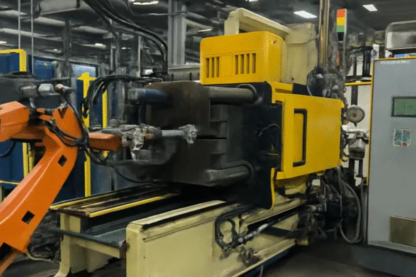 Industrial robotic arm and die-casting machine in a manufacturing facility.