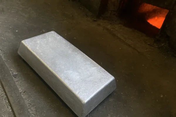 Close-up of an aluminum ingot placed in front of a furnace, ready for melting and processing.