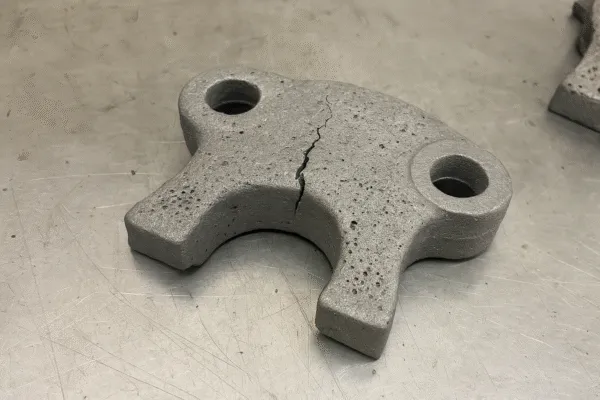 Close-up of a cracked metal casting showing visible defects and flaws, indicating a manufacturing issue.