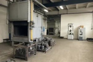 Heat treatment room with industrial furnaces and material testing equipment, showcasing heat-treated components in a manufacturing facility.
