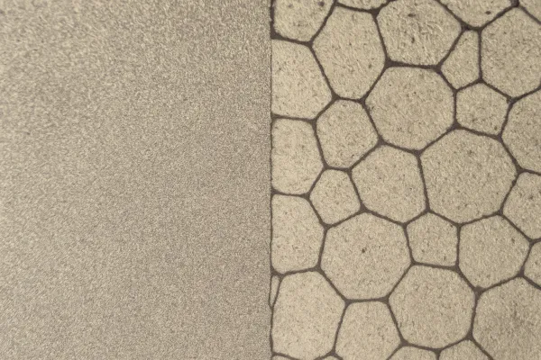 Close-up of a metal surface with contrasting textures, showing a smooth finish on the left and a hexagonal pattern on the right.