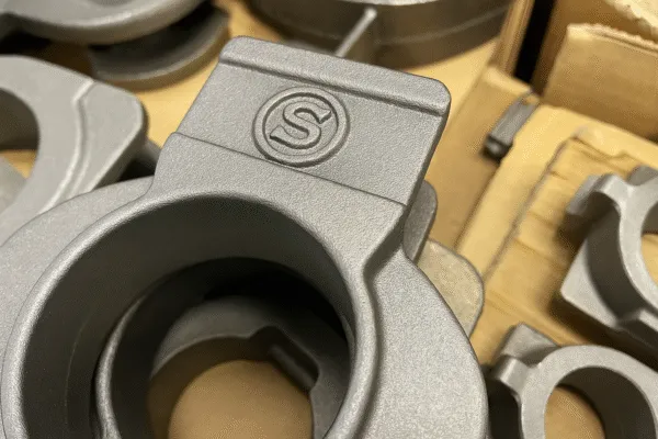Close-up of a metal casting with a branded logo, showcasing fine details and high-quality surface finish.