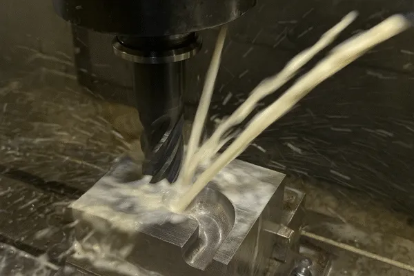 Close-up of CNC machining process with coolant splashing over the workpiece.