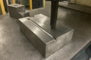 Close-up of a CNC milling machine working on a metal part with a horizontal groove.