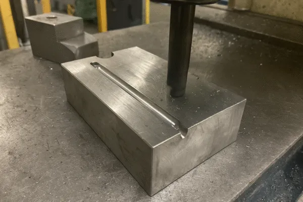 Close-up of a CNC milling machine working on a metal part with a horizontal groove.
