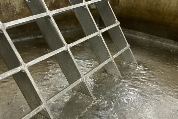 Galvanized steel grating submerged in water, showing the mesh pattern.
