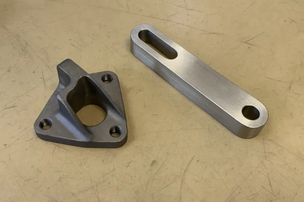 Close-up of two metal parts, one with a triangular shape and the other with a rectangular shape, showcasing precision machining.