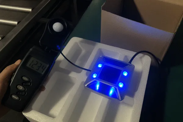 Solar-powered road marker being tested with a light meter for functionality verification.