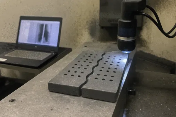 Quality inspector checking grate bar surface finish and air slot geometry with CMM probe and ultrasonic testing equipment.