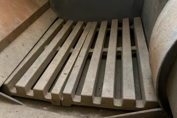 Heat-resistant grate bars arranged in a biomass boiler feed zone, showing longitudinal air slots.