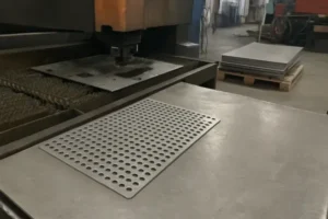 Laser cut perforated sheet metal panel on worktable in a sheet metal fabrication workshop