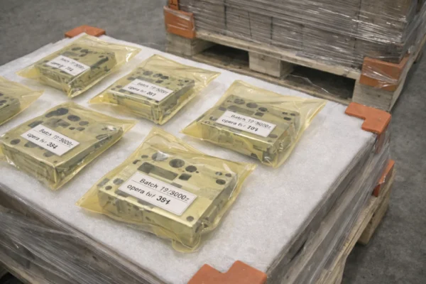 Export-ready packaging of machined parts in VCI anti-rust bags on foam layers, with traceability batch labels and a stretch-wrapped pallet secured by corner protectors.
